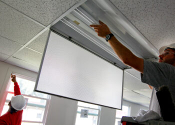 Construction workers install new energy-efficient windows and lighting. (U.S. Navy photo by Greg Vojtko, Public domain, via Wikimedia Commons)