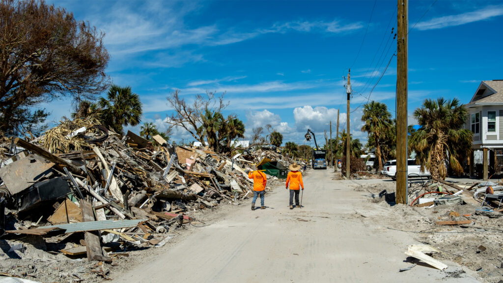 Workers walk past piles of debris in Fort Myers Beach, following the destruction caused by Hurricane Ian. (iStockphoto image)