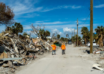 Workers walk past piles of debris in Fort Myers Beach, following the destruction caused by Hurricane Ian. (iStockphoto image)