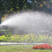 A woman watering a flower bed with a hose. (iStockphoto image)