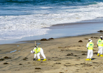 Environmental workers clean up beach after large oil spill off Huntington Beach, California. (iStockphoto image)