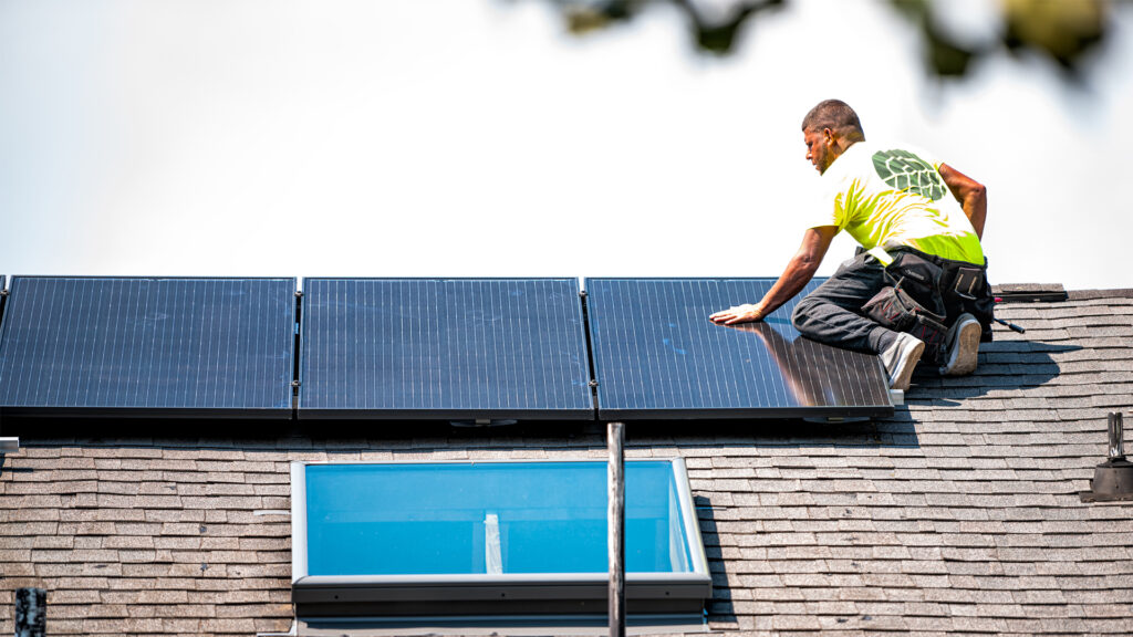 A worker installs solar panels on a home. (iStockphoto image)