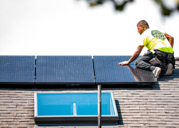 A worker installs solar panels on a home. (iStockphoto image)