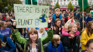 A young woman holds a sign at a climate change protest. (iStockphoto image)