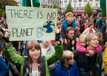 A young woman holds a sign at a climate change protest. (iStockphoto image)