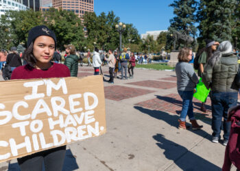 A demonstrator holds a sign at a climate protest in Denver. (Streetsblog Denver, CC BY 2.0, via Wikimedia Commons)