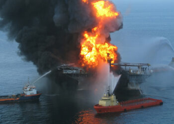 A Coast Guard rescue helicopter and crew document the fire aboard the mobile offshore drilling unit Deepwater Horizon on April 20, 2010. (US Coast Guard, via Wikimedia Commons)
