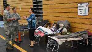 Florida Air National Guardsmen assist citizens at a special needs shelter at Atlantic Coast High School in Jacksonville in 2017, as part of the response to Hurricane Irma. (Master Sgt. William Buchanan/Florida National Guard Public Affairs Office, via Wikimedia Commons)