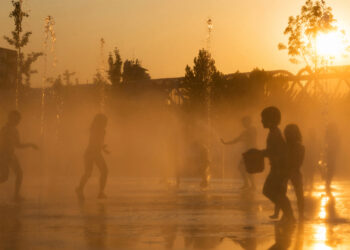 Children get relief from a heat wave in the jets of a fountain. (iStock image)