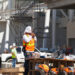 A construction worker ties a towel around his head while another worker can be seen drinking water from a gallon jug on a hot day. (iStock image)
