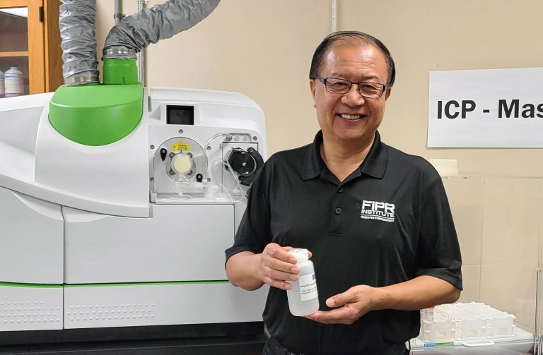 Dr. Patrick Zhang, research director of phosphate beneficiation and mining at the Florida Industrial and Phosphate Research Institute, part of Florida Polytechnic University, shows a solution containing rare earth minerals in the institute’s lab. (Photo courtesy of Florida Polytechnic University)