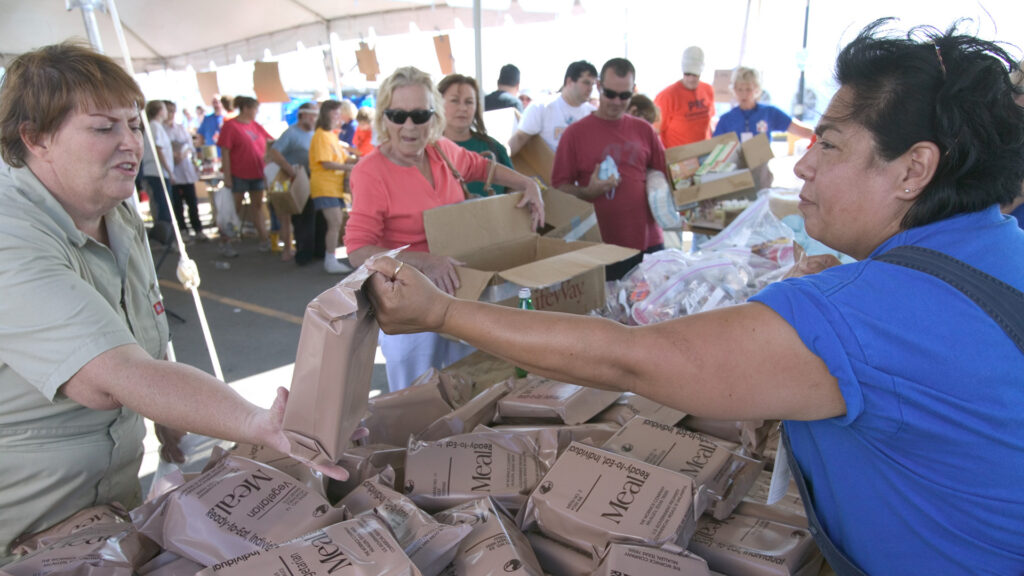 Ready-to-eat meals are distributed at a recovery center after Hurricane Katrina. (Andrea Booher, Public domain, via Wikimedia Commons)