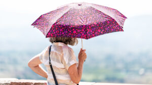 A woman holds an umbrella to block the sun. (iStock image)