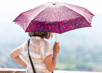 A woman holds an umbrella to block the sun. (iStock image)