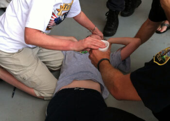A young man is assisted after passing out from the heat. (Tony Alter, CC BY 2.0, via Flickr)