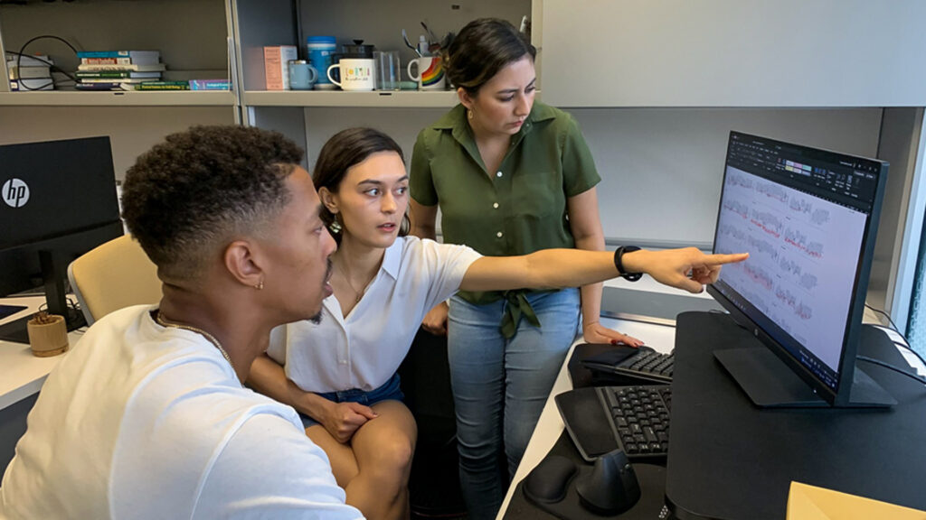 Lynée Turek-Hankins, center, points to a graph showing temperature fluctuations inside of a Miami-Dade household, as Nkosi Muse, left, and Mayra Cruz look on. (University of Miami photo)