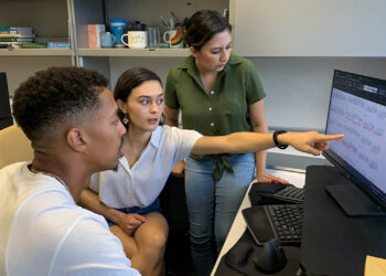 Lynée Turek-Hankins, center, points to a graph showing temperature fluctuations inside of a Miami-Dade household, as Nkosi Muse, left, and Mayra Cruz look on. (University of Miami photo)