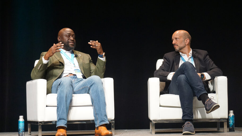 Newton Sanon, president and CEO of OIC of South Florida, speaks at the 15th Annual Southeast Florida Climate Leadership Summit as Ivan Rapin-Smith, president of Watsco Ventures, listens. (Naomi von Bose photo)