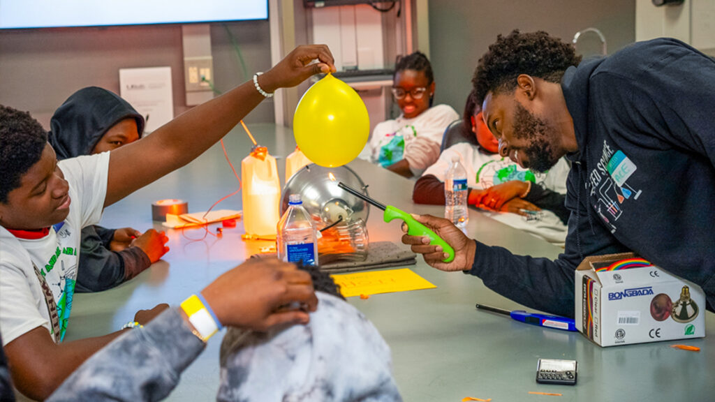 Ace Armand, a master’s student in biochemistry and molecular biology, heats a water-filled balloon to demonstrate how the world’s oceans absorb massive amounts of heat. (Daniel Menendez/University of Miami)