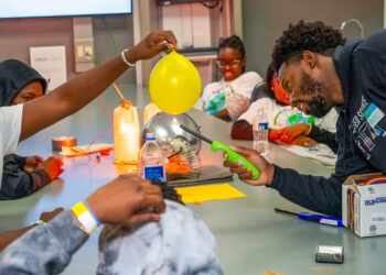 Ace Armand, a master’s student in biochemistry and molecular biology, heats a water-filled balloon to demonstrate how the world’s oceans absorb massive amounts of heat. (Daniel Menendez/University of Miami)