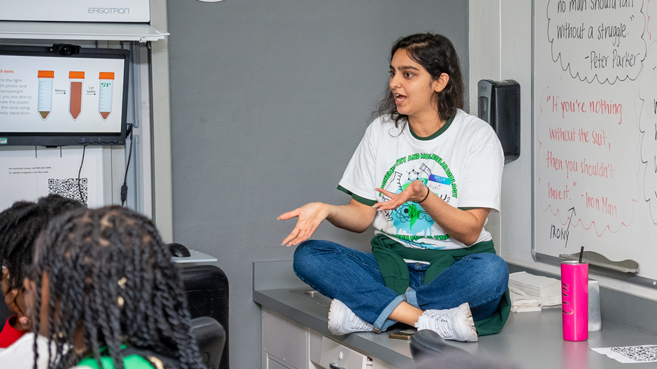 Avni Bhalgat, a Ph.D. candidate in the Miller School's cancer biology program, talks to Edison High students about microplastics at one of the six demonstration stations created for the outreach event. (Daniel Menendez/University of Miami)
