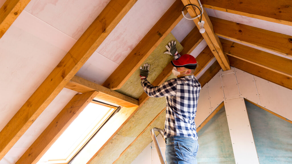 A worker installs insulation in an attic. (iStock image)