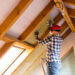 A worker installs insulation in an attic. (iStock image)