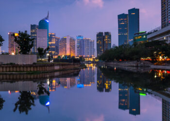 Office buildings reflected in the water in Jakarta, Indonesia. Indonesia is moving its capital 800 miles from Jakarta to Nusantara in large part because Jakarta is sinking to groundwater extraction. (iStock image)