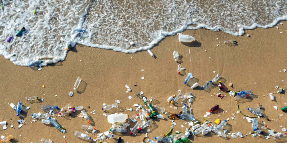 A wave pushes plastic pollution on a beach. (iStock image)
