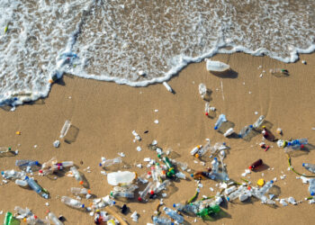 A wave pushes plastic pollution on a beach. (iStock image)