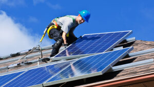 A worker installs solar panels on a rooftop (iStock image)