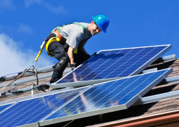 A worker installs solar panels on a rooftop (iStock image)