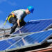 A worker installs solar panels on a rooftop (iStock image)