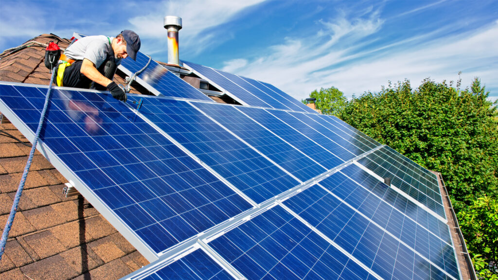 A worker installs solar panels on a rooftop (IStock image)