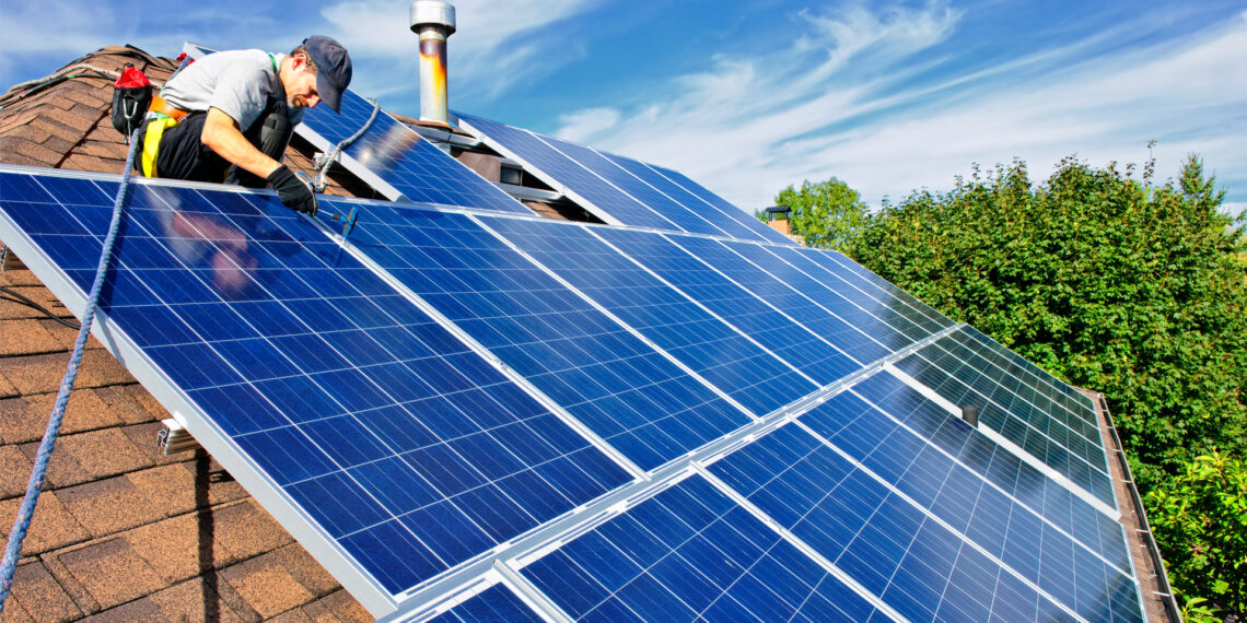 A worker installs solar panels on a rooftop (IStock image)