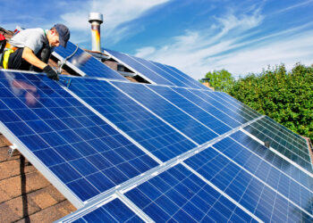 A worker installs solar panels on a rooftop (IStock image)
