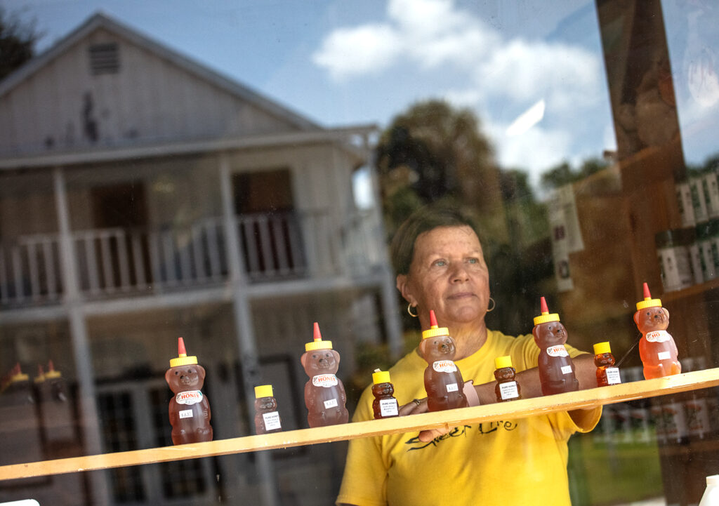 LaBelle, Florida: Rene Pratt leans on shelves with honey bottles at her family’s store, Harold P. Curtis Honey Co. in LaBelle, Florida near the Caloosahatchee Canal as it flows southwest from Lake Okeechobee. Harold P. Curtis Honey Co. was established in 1954. (Patrick Farrell for WLRN)