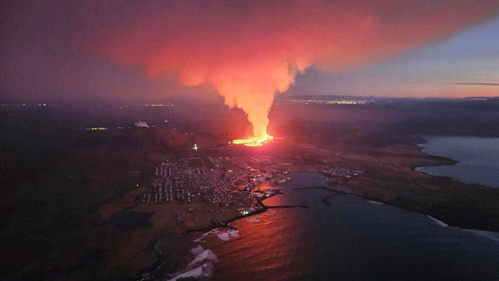Grindavík, Iceland, in the foreground with the 2024 volcanic eruption and lights of Reykjavík in the background (Almannavarnadeild ríkislögreglustjóra, Public domain, via Wikimedia Commons)