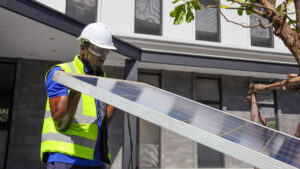 A worker lifts a solar panel. (iStock image)