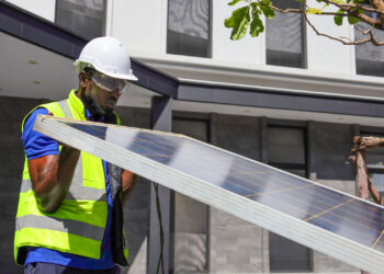A worker lifts a solar panel. (iStock image)