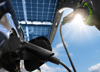 An electric vehicles is charged from a charging station that gets energy from solar panels. (iStock image)