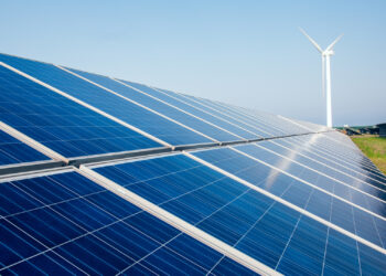 Solar panels with wind turbines in the background (iStock image)