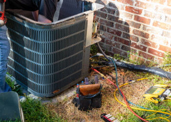 A technician repairs a home air conditioning unit. (iStock image)