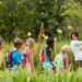 A young teacher with children on a nature field trip. Moving away from the structures and competition of indoor classroom settings matters for students. (iStock image)
