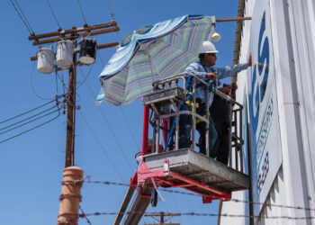A worker uses an umbrella to shade himself from the heat (Getty Images via Grist).