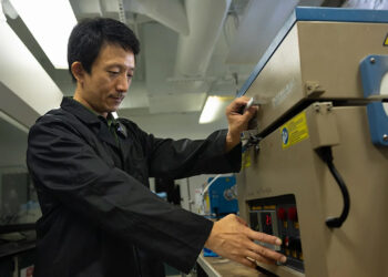 Yang Yang, an associate professor in UCF’s NanoScience Technology Center, works with a device that helped develop his triple-phase device that captures and converts carbon dioxide. (Photo by Antoine Hart)