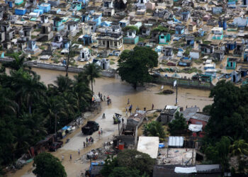 Haitian citizens walk through the flooded streets of Port-au-Prince in 2020 after Hurricane Tomas hit the country. (DVIDSHUB, CC BY 2.0, via Wikimedia Commons)