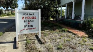 A for-sale sign in front of two properties in north Lake Charles, price negotiable. (Zoya Teirstein/Grist)