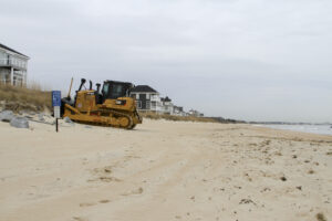 Heavy equipment is staged along the beach in Norfolk, Virginia’s East Ocean View neighborhood. Contractors will use the equipment to move dredged up sand on the beach to create a 60 foot wide beach berm that slopes to 5 feet above mean low water. Engineers’ designed the beach to absorb the wave energy, protecting critical infrastructure during coastal storms. (U.S. Army photo/Patrick Bloodgood, CC BY 2.0, via flickr)