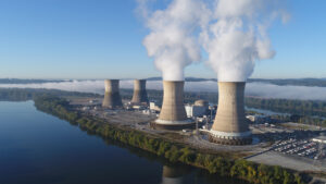 The Three Mile Island nuclear plant in 2019. The working cooling towers in the foreground are emitting water vapor. The dormant cooling towers are from Unit 2, which was permanently damaged in the 1979 accident. (Constellation Energy, CC BY-SA 4.0, via Wikimedia Commons)